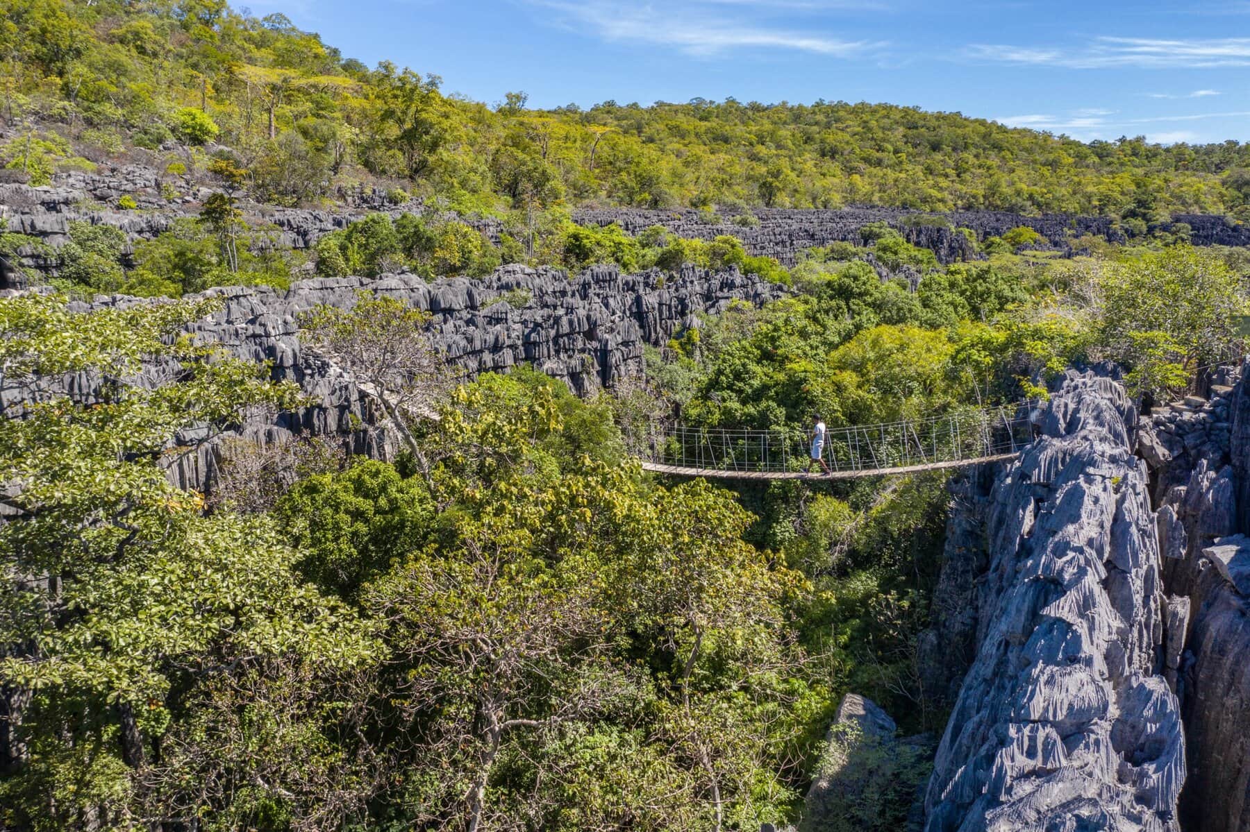A guest walking across a bridge at Ankarana reached on a helicopter adventure with Miavana by Time + Tide Madagascar