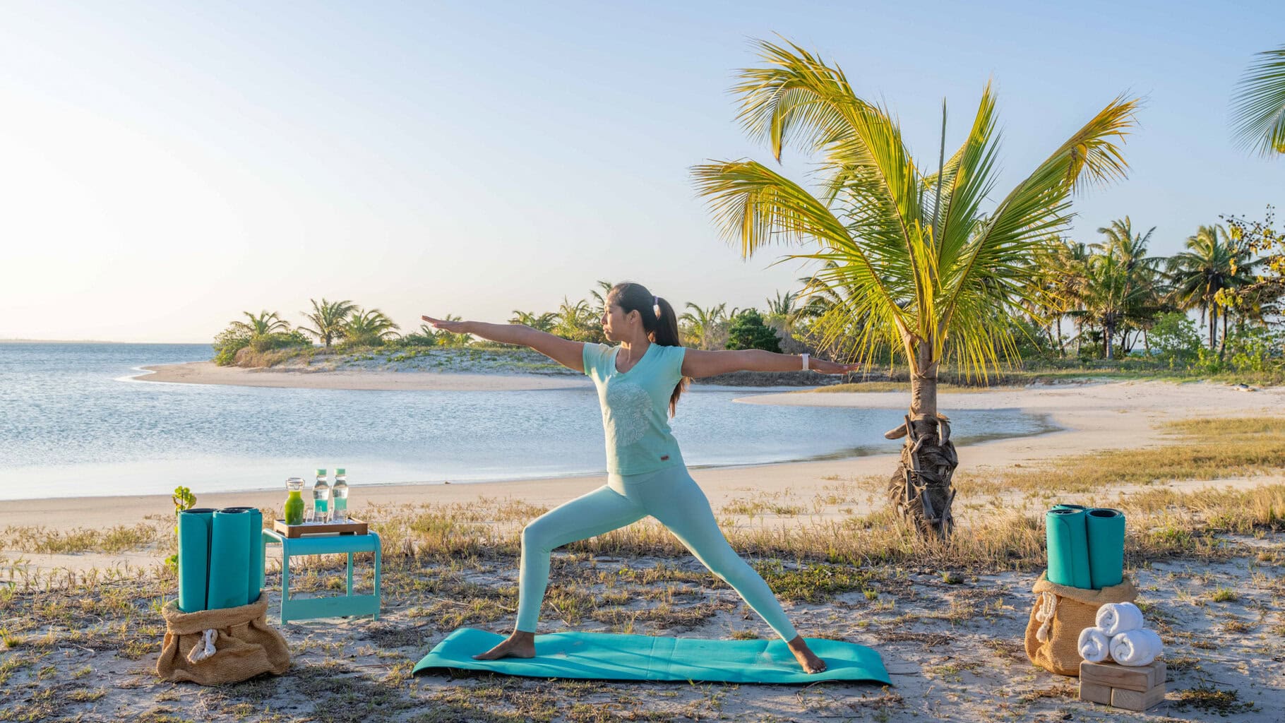 A woman striking a yoga pose on the beach at Miavana by Time + Tide in Madagascar