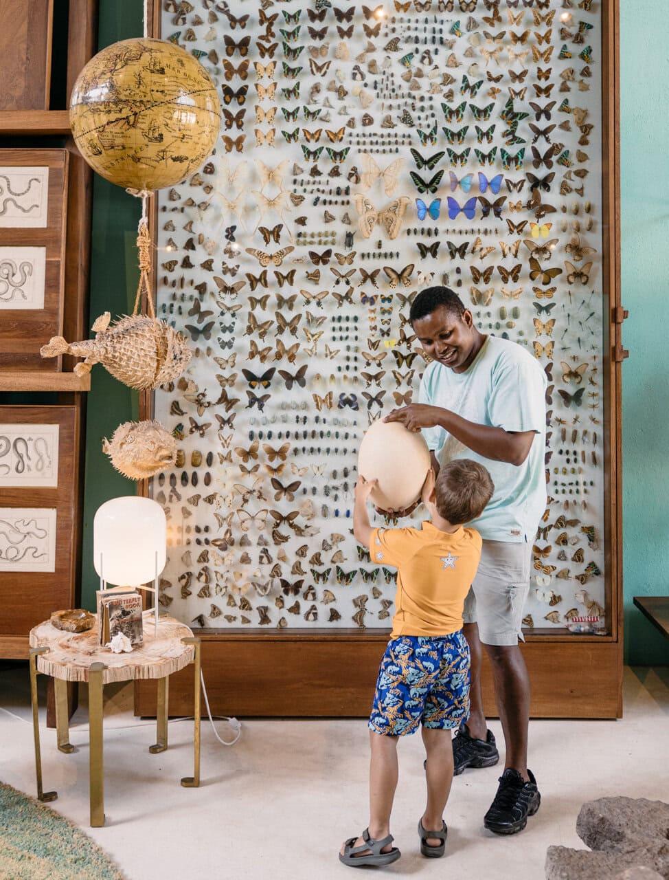 Child holding a fossil egg with the help of a guide in the cabinet of curiosities at Miavana