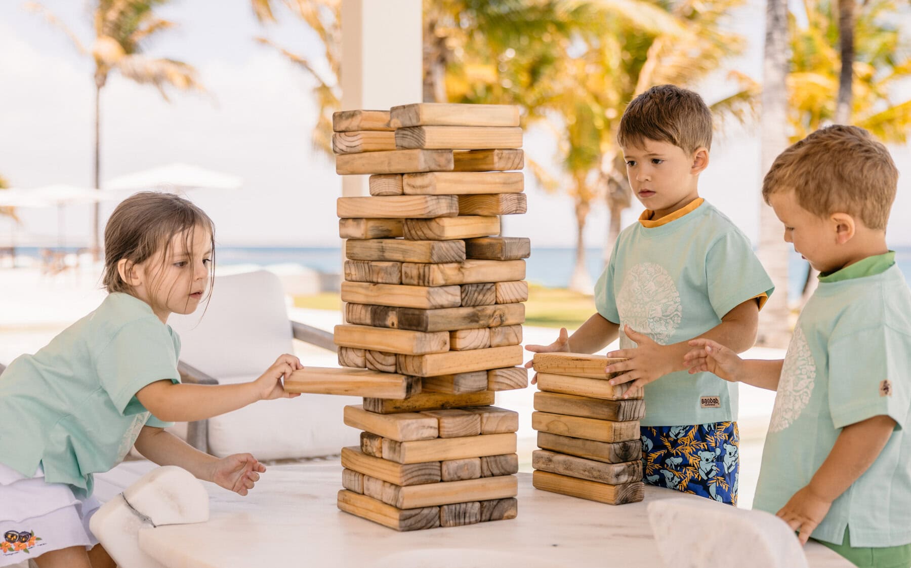 Three children playing giant jenga on a family holiday with Miavana by Time + Tide, Madagascar
