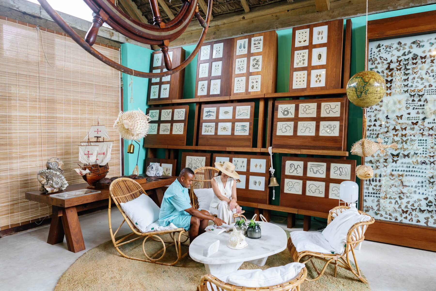 A woman sitting next to a guide going through one of the books in the Cabinet des Curiosities at Miavana, Madagascar